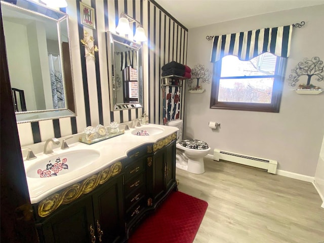 bathroom featuring wood-type flooring, vanity, toilet, and a baseboard heating unit