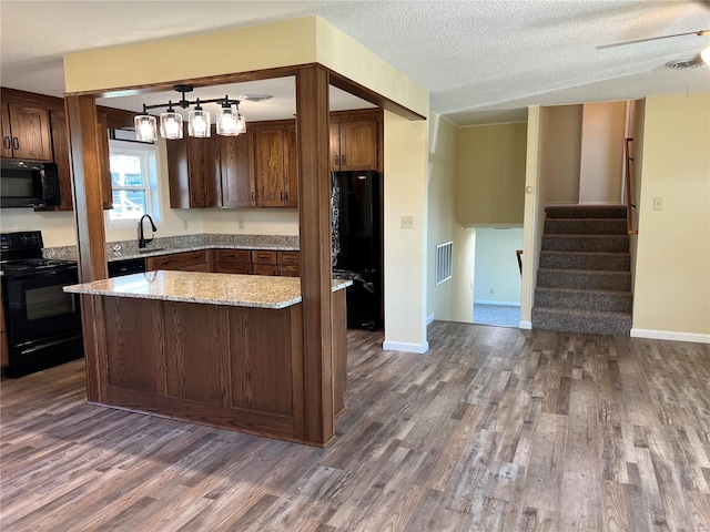 kitchen with light stone countertops, dark hardwood / wood-style flooring, a textured ceiling, sink, and black appliances