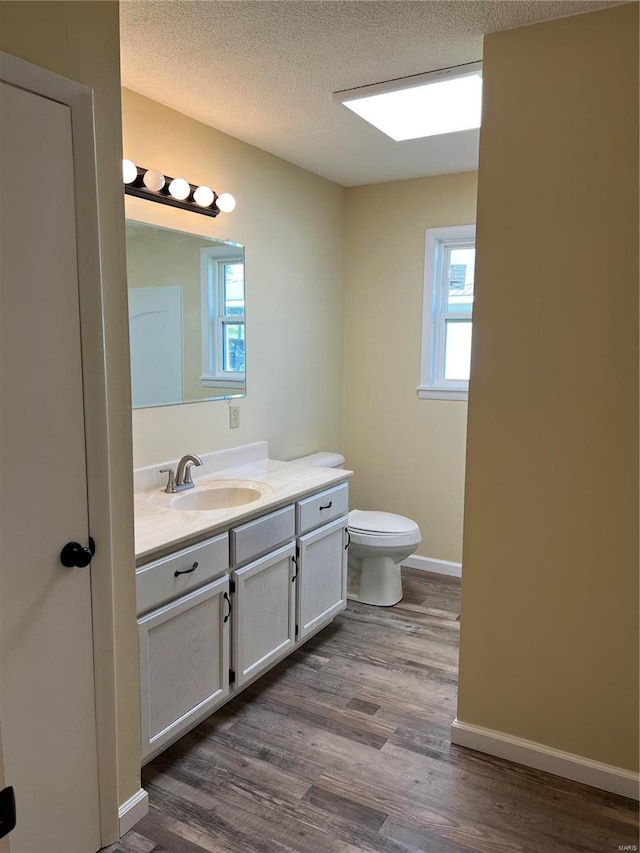 bathroom featuring wood-type flooring, vanity, a textured ceiling, and toilet