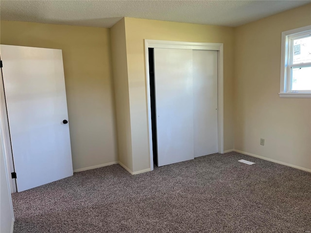 unfurnished bedroom with carpet, a textured ceiling, and a closet