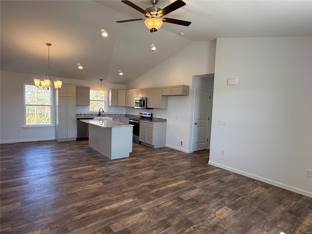 kitchen featuring appliances with stainless steel finishes, light stone counters, sink, decorative light fixtures, and a kitchen island