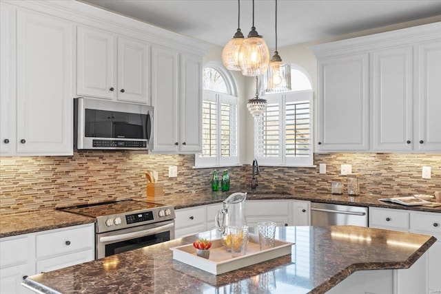 kitchen with sink, dark stone countertops, stainless steel appliances, a center island, and white cabinets