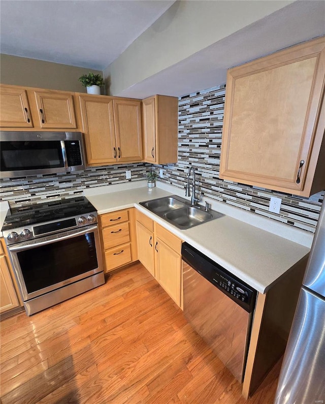 kitchen featuring appliances with stainless steel finishes, light brown cabinetry, tasteful backsplash, and sink