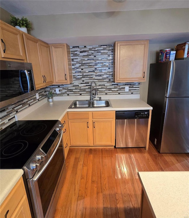 kitchen featuring stainless steel appliances, tasteful backsplash, light brown cabinetry, light hardwood / wood-style flooring, and sink