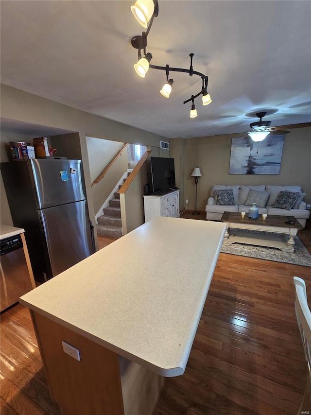 kitchen with ceiling fan, a center island, dark wood-type flooring, track lighting, and stainless steel appliances