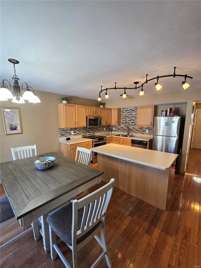 kitchen featuring stainless steel appliances, decorative backsplash, a notable chandelier, a kitchen island, and sink