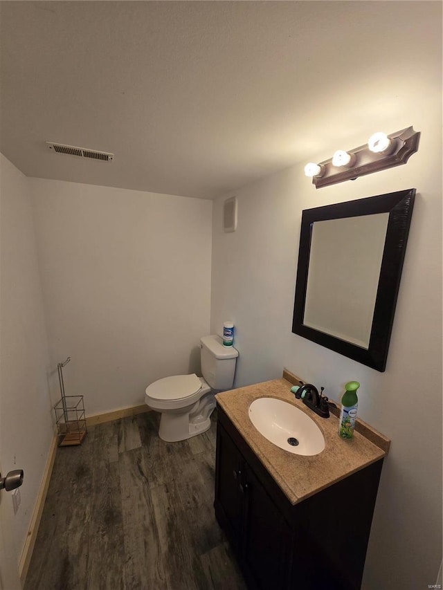 bathroom featuring toilet, vanity, and hardwood / wood-style floors