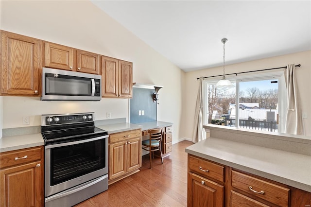 kitchen featuring stainless steel appliances, vaulted ceiling, light hardwood / wood-style flooring, and decorative light fixtures