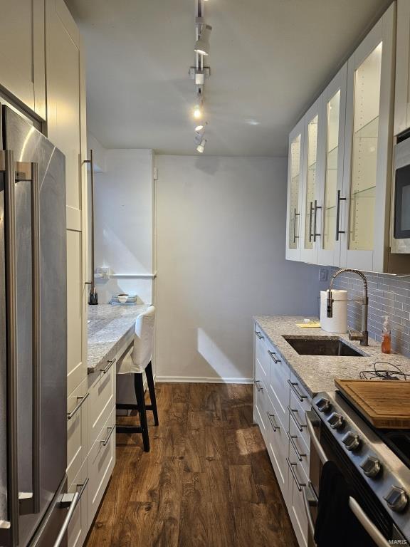 kitchen with light stone countertops, sink, stainless steel appliances, dark hardwood / wood-style floors, and white cabinets