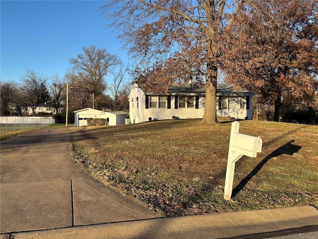 view of front facade featuring a garage, an outbuilding, and a front yard