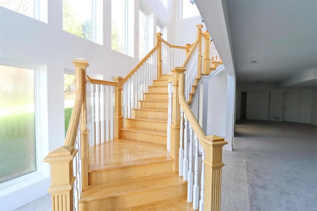 staircase featuring tile patterned flooring and a high ceiling