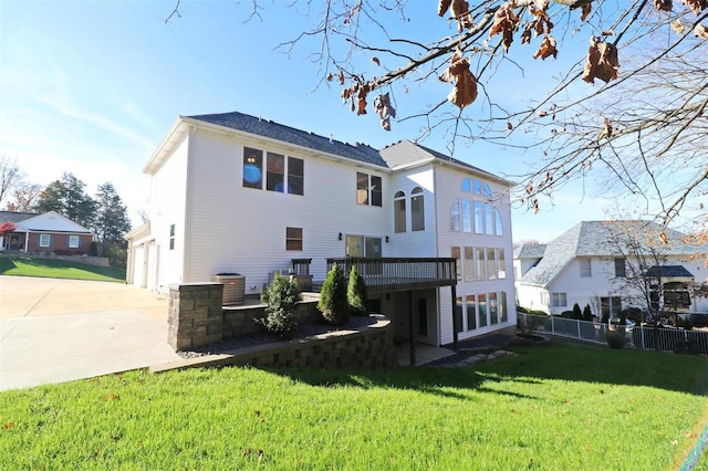 rear view of house with a lawn, a garage, and a deck