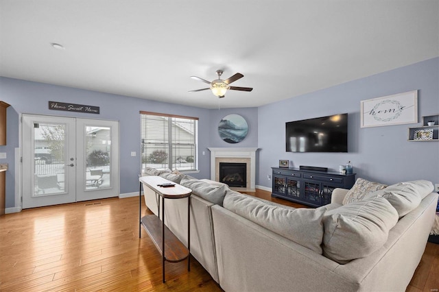 living room featuring wood-type flooring, french doors, and ceiling fan