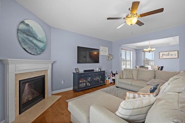 living room with a premium fireplace, dark hardwood / wood-style flooring, and ceiling fan with notable chandelier