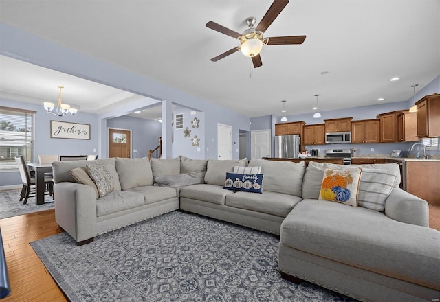 living room featuring wood-type flooring and ceiling fan with notable chandelier