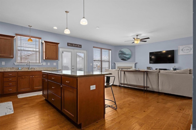 kitchen with pendant lighting, sink, hardwood / wood-style flooring, ceiling fan, and a kitchen island