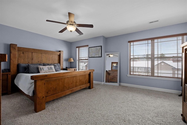 carpeted bedroom featuring multiple windows and ceiling fan