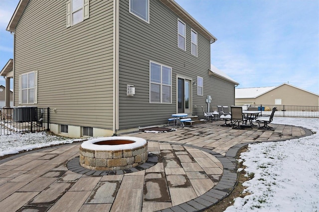 snow covered back of property featuring a patio area, central AC unit, and a fire pit