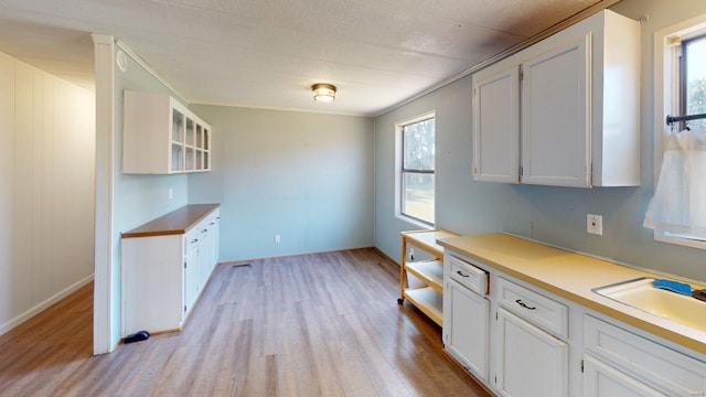 kitchen with plenty of natural light, white cabinetry, sink, and light hardwood / wood-style flooring