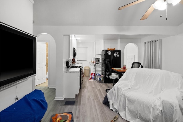 bedroom with ceiling fan, black refrigerator, and light hardwood / wood-style floors