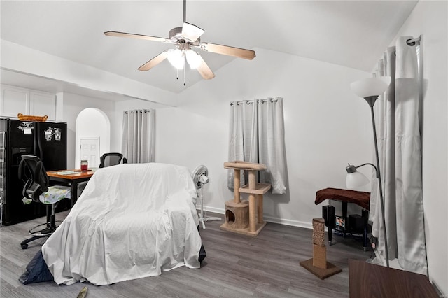 bedroom with hardwood / wood-style floors, ceiling fan, black refrigerator with ice dispenser, and vaulted ceiling