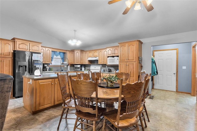 dining space featuring ceiling fan with notable chandelier, sink, and vaulted ceiling