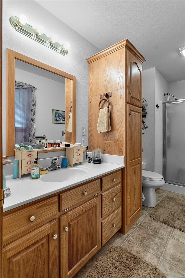 bathroom featuring vanity, a shower with door, tile patterned flooring, toilet, and a textured ceiling