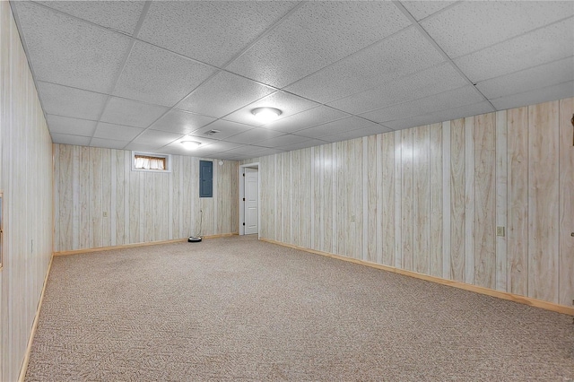 basement featuring carpet flooring, electric panel, wood walls, and a drop ceiling