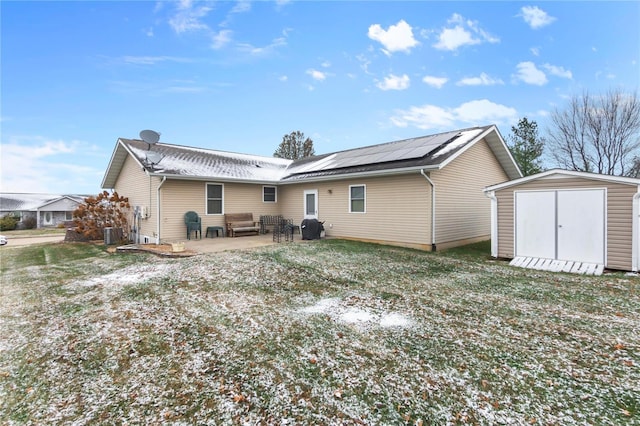 back of house with a lawn, a storage unit, solar panels, central AC, and a patio