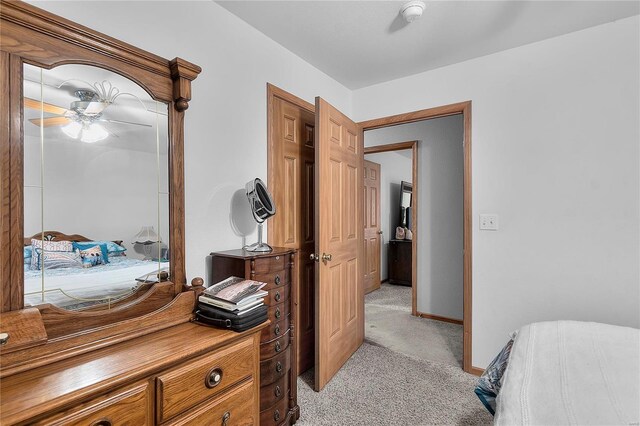 bedroom featuring light colored carpet, a ceiling fan, and baseboards