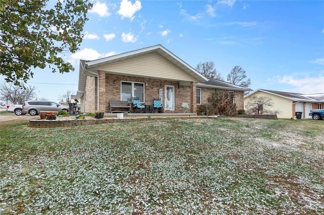 view of front of home featuring a front yard, a porch, and brick siding