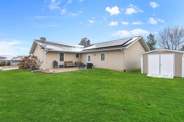 back of house featuring a patio, an outbuilding, solar panels, a storage unit, and a lawn