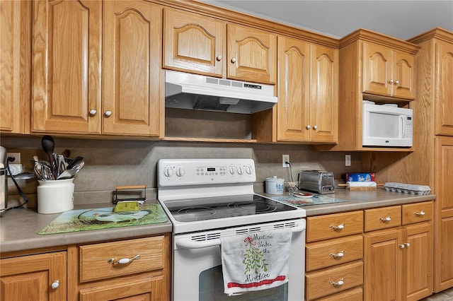 kitchen with under cabinet range hood, white appliances, and light countertops