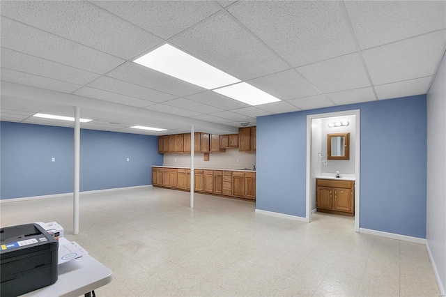 finished basement featuring light floors, baseboards, and a sink