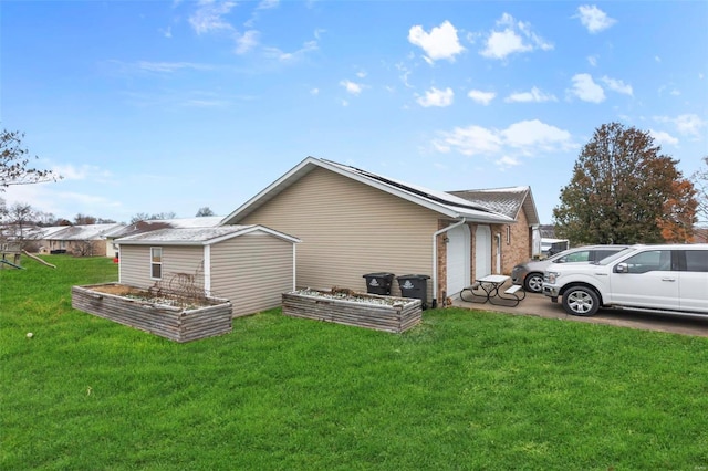 view of side of property featuring a vegetable garden, a lawn, brick siding, and a garage