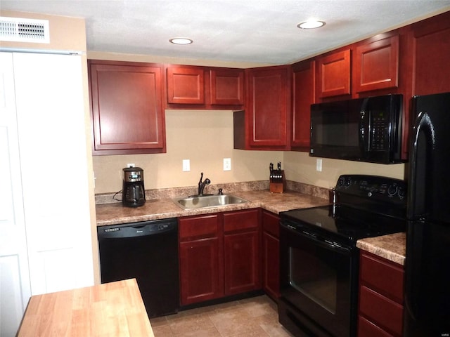 kitchen featuring black appliances, light tile patterned floors, and sink