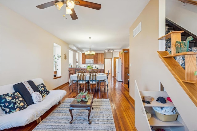 living room featuring ceiling fan with notable chandelier and hardwood / wood-style flooring