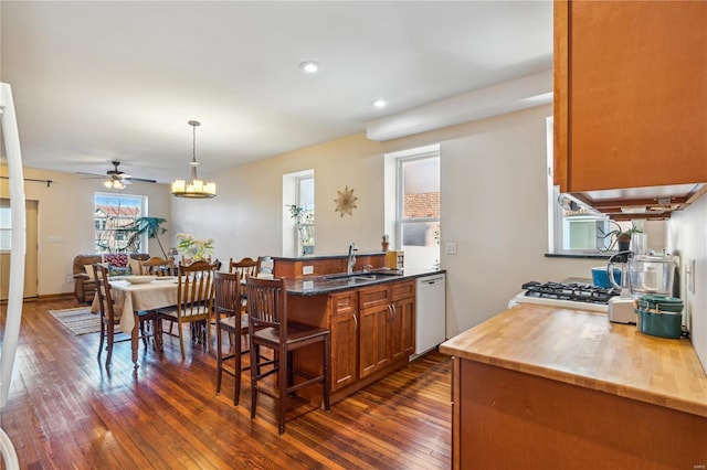 kitchen featuring decorative light fixtures, dishwasher, dark hardwood / wood-style floors, and sink