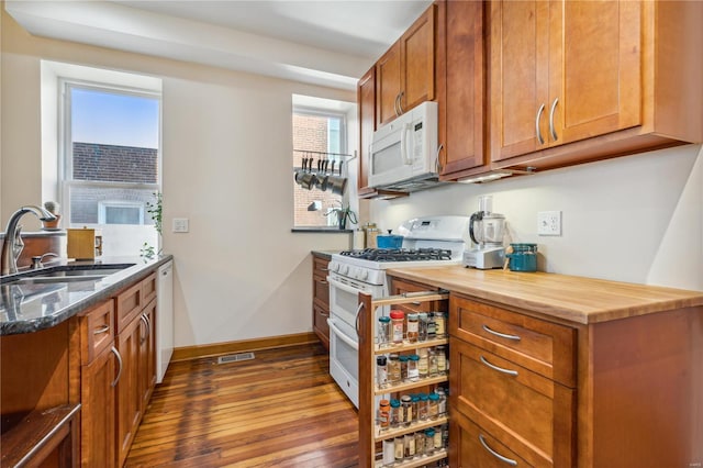 kitchen with sink, dark stone countertops, hardwood / wood-style flooring, and white appliances