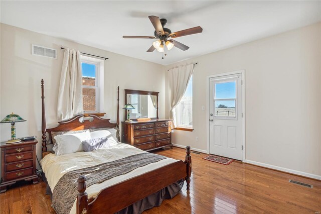 bedroom featuring ceiling fan, dark wood-type flooring, and multiple windows