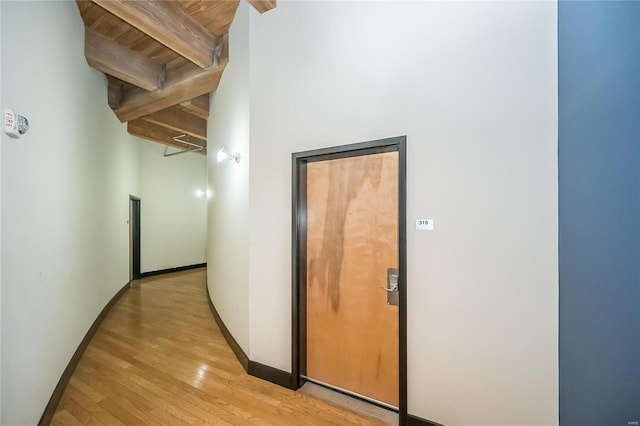 corridor featuring beamed ceiling, wooden ceiling, and light hardwood / wood-style flooring