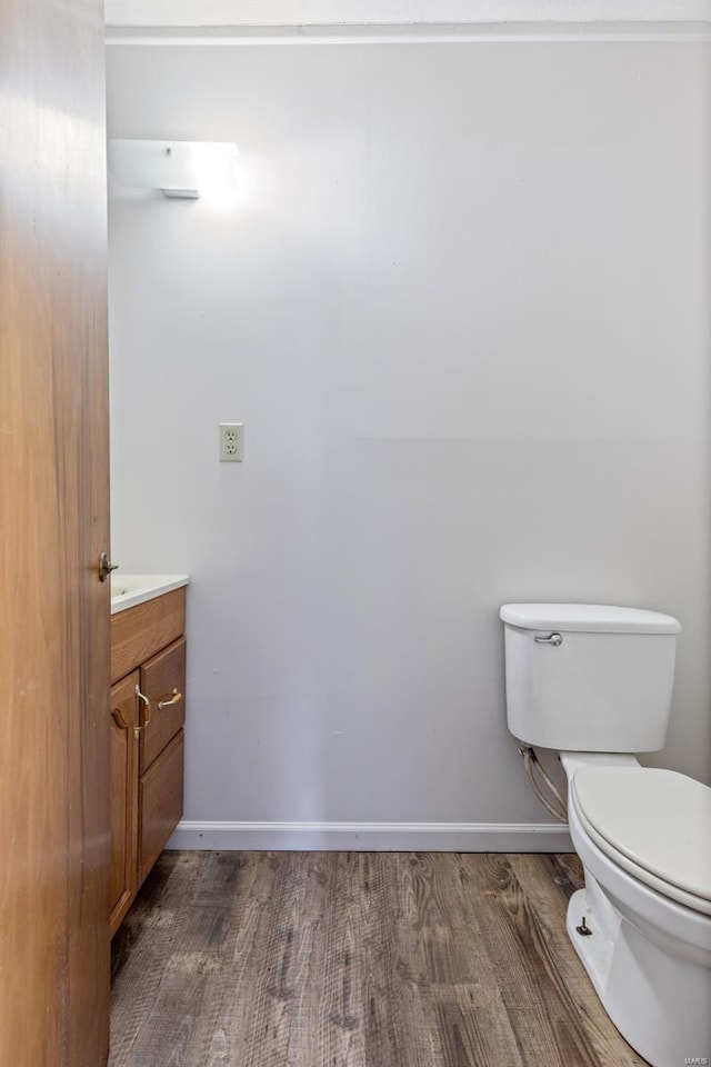 bathroom featuring wood finished floors, vanity, toilet, and baseboards