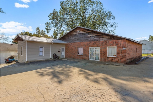rear view of property featuring brick siding and metal roof