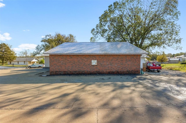 view of property exterior with brick siding and metal roof