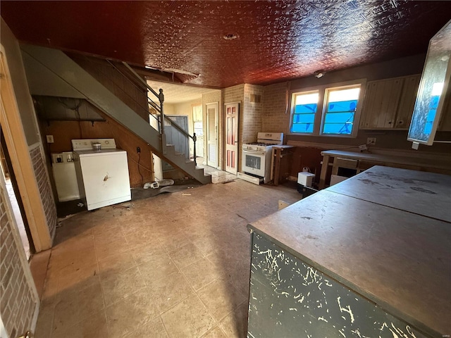 kitchen with white gas range oven, brick wall, and washer / dryer