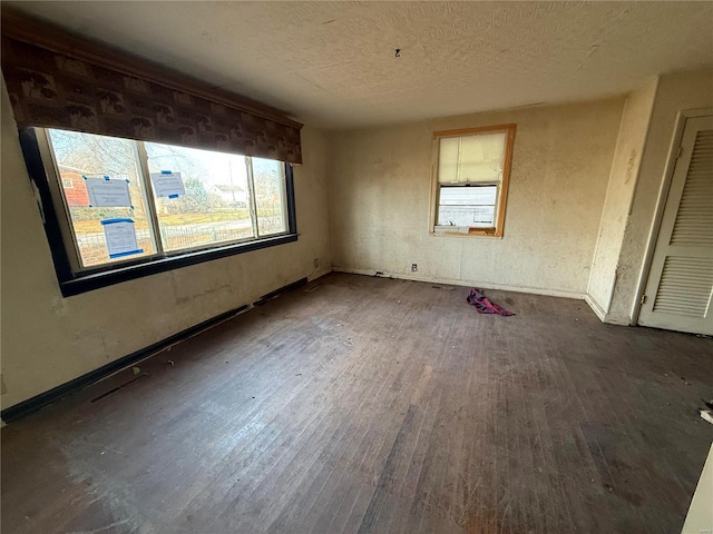 unfurnished room with dark wood-type flooring and a textured ceiling