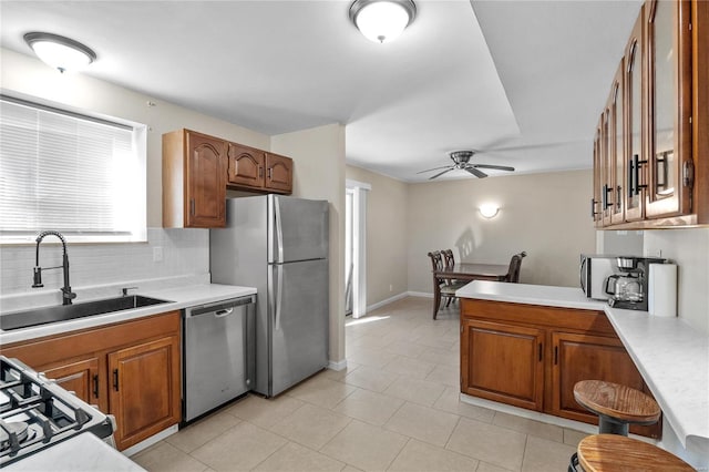 kitchen featuring sink, ceiling fan, decorative backsplash, kitchen peninsula, and stainless steel appliances