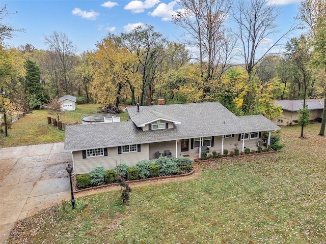 view of front of home with a front yard, covered porch, and a storage shed