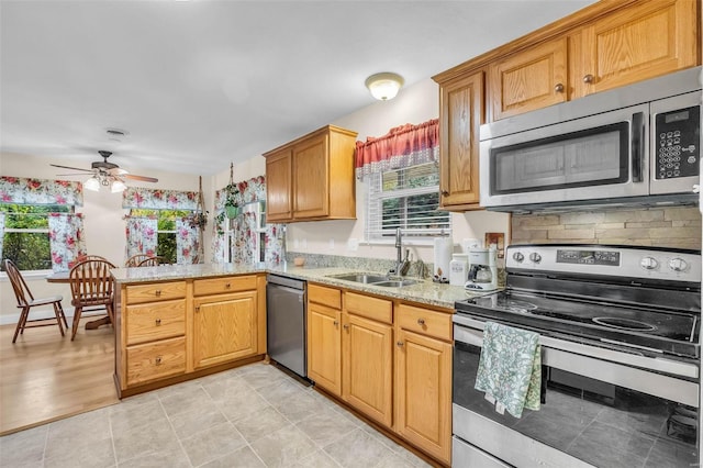 kitchen with kitchen peninsula, a wealth of natural light, stainless steel appliances, ceiling fan, and sink