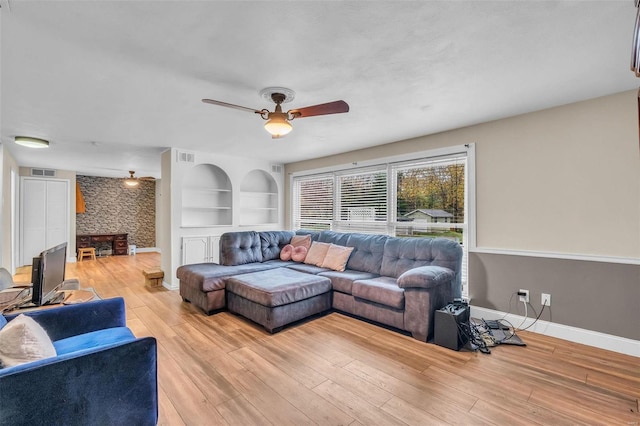 living room featuring ceiling fan, light wood-type flooring, and built in features